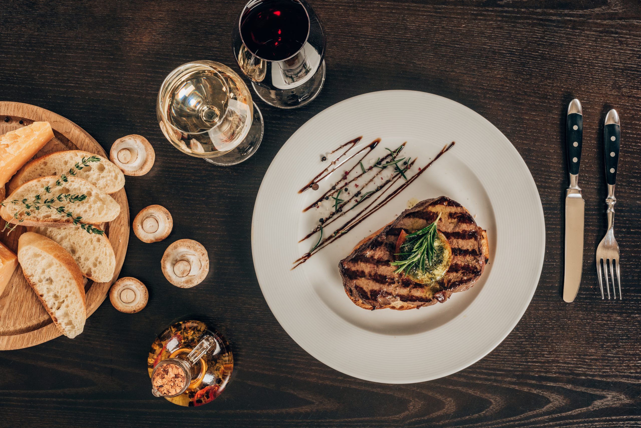 top view of beef steak, baguette and wine on table